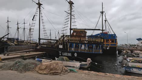 Djerba-port-with-fishermen-boats,-nets-and-touristic-pirate-galleon-ships,-third-part