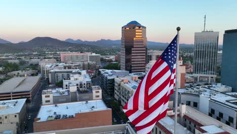 American-flag-waving-in-front-of-Tucson,-Arizona-downtown-skyline
