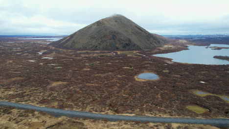 lake-Myvatn,-Vindbelgjarfjall:-aerial-view-traveling-out-to-the-beautiful-icelandic-lake-and-a-volcano-on-a-sunny-day