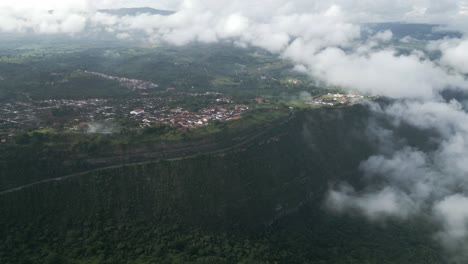 Aerial-view-of-Barichara-town-of-Colombia-surrounded-by-greenery,-mountain-cliff-under-cloudy-sky