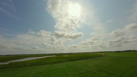 Drohne-Fliegt-Tief-über-Den-Grasfeldern-In-Richtung-Himmel-Und-Zeigt-Die-Sonne-Und-Die-Wolken