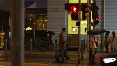 Toma-Nocturna-De-Personas-Cruzando-La-Calle-Con-Semáforos-En-Verde-En-Hong-Kong