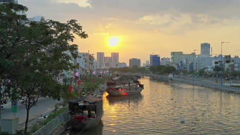 Captura-La-Impresionante-Belleza-De-Una-Puesta-De-Sol-Sobre-El-Puerto-De-Binh-Dong-Durante-El-Festival-De-Las-Flores,-Con-Los-Barcos,-El-Río-Y-El-Paisaje-Urbano-Como-Telón-De-Fondo-Impresionante