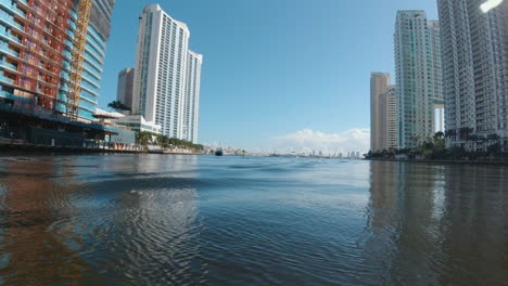 view-from-a-small-watercraft-as-it-passes-through-the-calm-waters-of-a-narrow-channel-with-tall-buildings-on-either-side-Miami-Florida