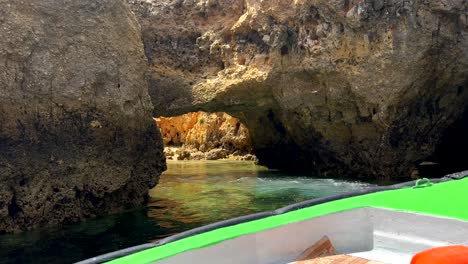 Pov-shot-from-boat-showing-sandy-beach-in-cave-between-cliffs-of-Algarve-during-sunny-day---Stunning-place-with-clear-water-in-Portugal