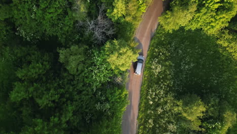 Top-down-view-of-grey-car-vehicle-driving-in-rural-road-in-summer-countryside