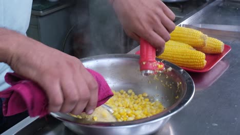 Close-up-scene-of-a-person-using-a-machine-to-remove-all-the-kernels-from-American-corn-cobs-and-pour-the-corn-into-the-can