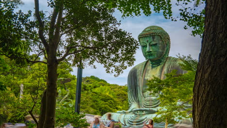 Timelapse-Great-green-buddha-of-Kamakura-bronze-Daibutsu-Japan-between-trees-and-Green-leaves-cloudy-summer-day