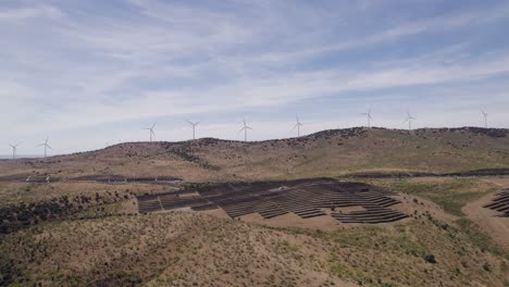 Green-energy-from-solar-panels-and-wind-turbines,-rising-aerial-in-Spanish-Countryside