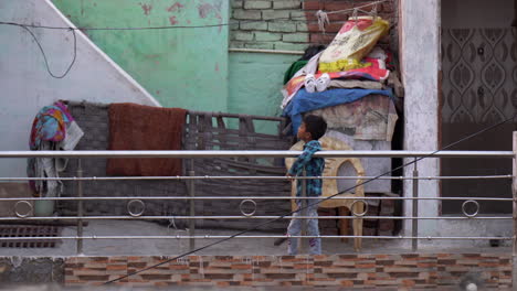 Young-Indian-boy-in-jeans-stands-at-balcony-railing-in-Agra,-India