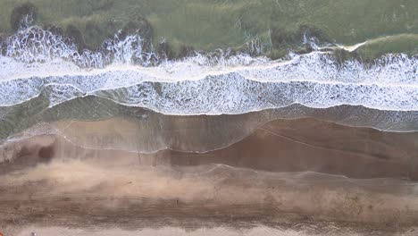 Static-top-down-drone-shot-of-a-beach-in-Cariló,-Argentina-with-waves-crashing-on-the-shore