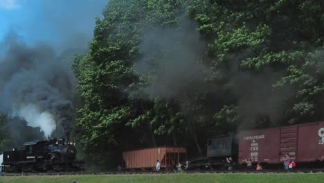 Ein-Blick-Auf-Eine-Höhepunkt-Dampfmaschine,-Die-Sich-Nähert,-Rauch-Und-Dampf-Ausbläst-Und-An-Einem-Sonnigen-Sommertag-An-Güterwaggons-Vorbeifährt