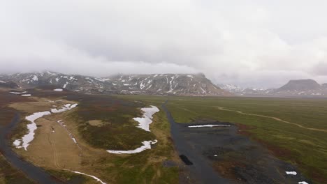 Aerial-view-of-mountains-with-melting-snow,-on-a-cloudy-and-foggy-day,-Iceland