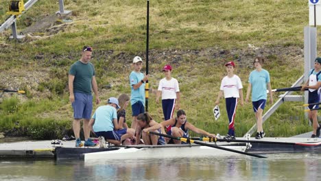 Zwei-Rudererinnen-Im-Doppelzweier-Am-Pier,-Während-Ein-Trainer-Das-Boot-Verlässt