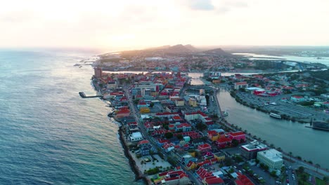 4k-aerial-flying-over-Willemstad-city-and-Pietermaai-District-in-Curacao,-during-golden-hour-sunset