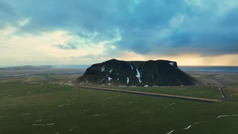 Aerial-landscape-view-of-Petursey-Mountain,-Iceland,-with-a-dramatic-cloudscape,-at-dusk