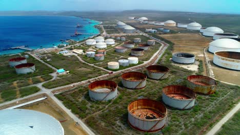 4k-upwards-aerial-reveal-of-oil-storage-tanks-and-silos,-truck-driving-through-Bullenbaai-Oil-Terminal-in-Curacao