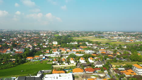 Aerial-rising-shot-of-Canggu-with-Houses-and-farm-fields-during-sunny-day-on-Bali-island