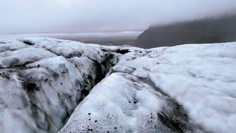 Iceland---Glacier-Wonderland:-A-hiker-walks-through-a-wonderland-of-ice-formations-on-Falljökull-glacier,-the-blue-ice-sparkling-in-the-sunlight
