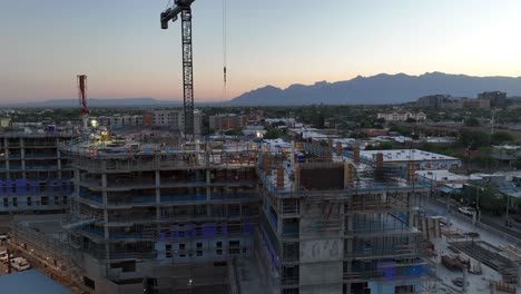 Construction-of-new-inner-city-skyscraper-with-sunrise-over-mountain-range-in-background