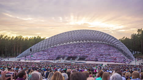 Timelapse-shot-of-huge-crowd-of-people-gathered-for-Latvian-Song-and-Dance-Festival-in-an-outdoor-stadium-on-a-cloudy-day