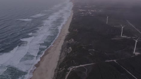 Panoramic-shot-of-Praia-da-Areeira-Portugal-with-windturbines-during-sunrise,-aerial