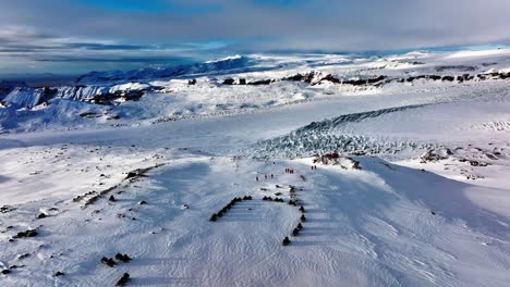 Aerial-landscape-view-of-people-looking-at-the-Myrdalsjokull-glacier-panorama,-after-riding-snowmobiles-in-Iceland,-at-dusk