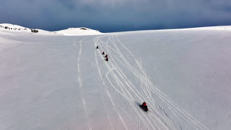 Vista-Aérea-De-Personas-Montando-Motos-De-Nieve-En-El-Suelo-Helado-Del-Glaciar-Myrdalsjokull-En-Islandia