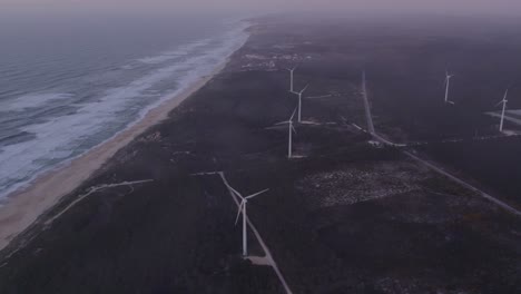 Windturbines-at-Praia-do-Norte-Portugal-during-morning-with-low-clouds,-aerial