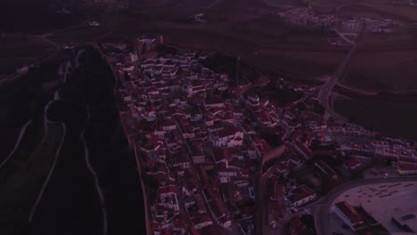 Enthüllen-Sie-Eine-Aufnahme-Der-Historischen-Ummauerten-Stadt-Obidos,-Portugal,-Während-Eines-Farbenprächtigen-Sonnenaufgangs-Aus-Der-Luft