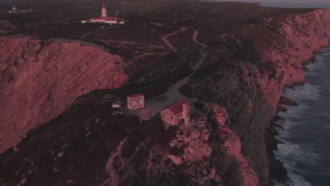 Old-ruine-at-high-cliff-at-Farol-do-cabo-Espichel-Portugal-during-sunset,-aerial