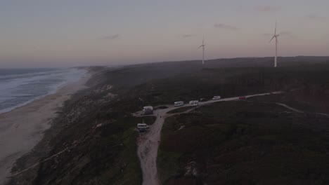 Campers-standing-in-front-of-Praia-da-Areeira-Portugal-during-sunset,-aerial