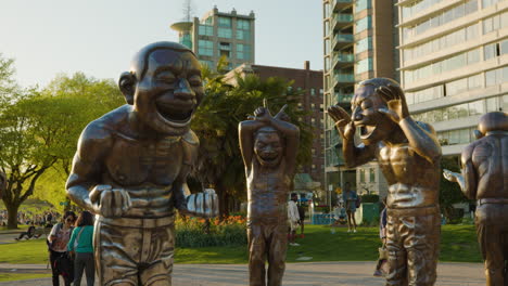 Close-up-of-Laughing-Statues-at-Morton-Park,-Vancouver,-Gimbal-sunset