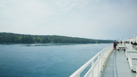 People-Enjoying-Beautiful-Forested-Shoreline-View-from-Deck-of-Ferry