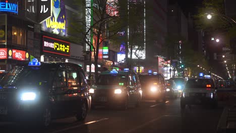 Eine-Reihe-Von-Taxis,-Die-Sich-Nachts-In-Sapporo-Langsam-Entlang-Der-Straße-Bewegen