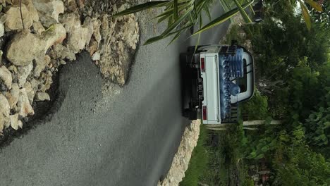 Vertical-Driving-pick-up-truck-with-empty-plastic-jugs-or-big-empty-plastic-water-bottles-while-driving-on-the-road-of-Nusa-Penia-in-Bali-Indonesia-in-slow-motion