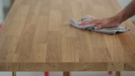 Man-drying-a-new-wooden-table-with-a-rag-in-slow-motion