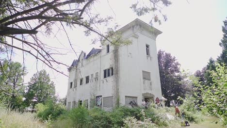 Old-abandoned-mansion-with-urban-explorers-walking-in-to-the-building