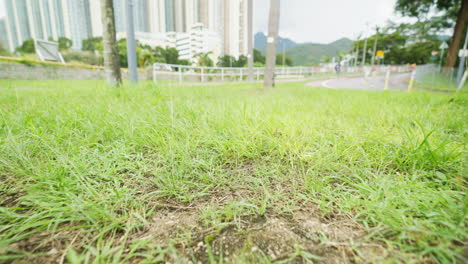 Low-gliding-wide-shot-cracked-grassy-soil-in-green-area-near-apartment-building