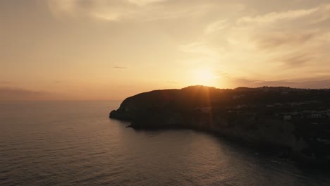 Szenischer-Orangefarbener-Sonnenuntergang-Am-Kap-Und-Offenem-Meer-Bei-Ischia-In-Italien,-Luftaufnahme