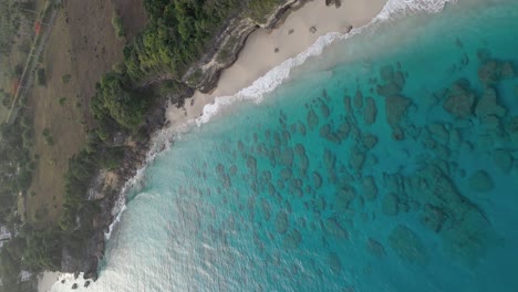 Vertical-birds-eye-shot-of-transparent-Caribbean-sea-water-with-coral-reef-and-sandy-beach-in-summer---Rocky-Coastline-of-Playa-Chencho,-Dominican-Republic