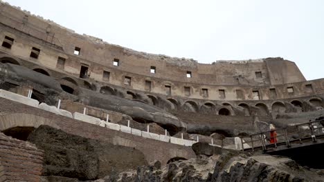 A-breathtaking-pan-shot-looking-up-at-the-walls-of-the-famous-Colosseum-from-the-underground-tunnels-of-the-arena-in-Rome,-Italy