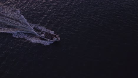 Top-down-of-speedboat-on-calm-ocean-at-Portugal-during-sunrise,-aerial