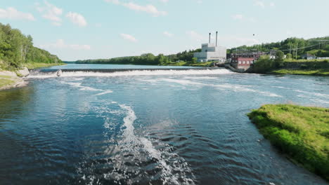Low-Aerial-Shot-Flies-Over-River-with-Hydroelectric-Dam-and-Power-Plant-in-the-Background,-Maine-USA