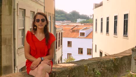 Beautiful-woman-with-red-dress-sitting-in-historic-place-in-Porto,-Portugal