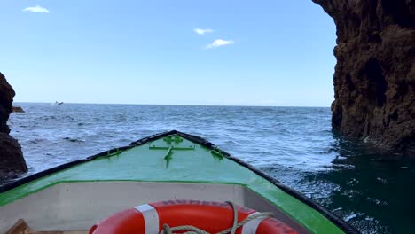 POV-Aufnahme-Auf-Einem-Alten-Boot,-Das-Im-Sommer-Zwischen-Den-Klippen-Der-Algarve-In-Den-Welligen-Atlantischen-Ozean-Fährt