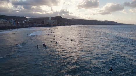 Surfers-waiting-for-waves-on-Las-Canteras-Beach-during-sunset,-Las-Palmas-de-Gran-Canaria
