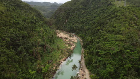 Cinematic-aerial-shot-moving-down-towards-a-blue-river-within-a-forest-in-Cebu-Philippines,-Drone,-Asia