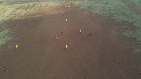 Local-soccer-teams-play-football-match-on-arid-pitch,-Loitokitok,-Kenya,-aerial