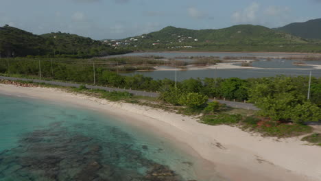 Antigua-and-Bermuda---2023:-aerial-view-Jeep-drives-on-caribbean-sandy-coast-surrounded-by-scenic-nature-and-blue-turquoise-water